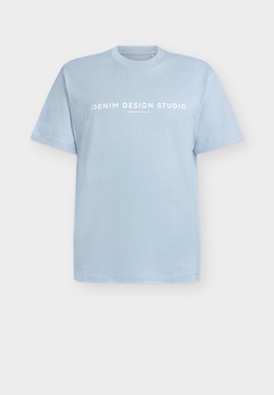 Gaiši zila kokvilnas t-krekls ar īsām piedurknēm un apaļu kakla izgriezumu. Uz krūtīm ir balts uzraksts "DENIM DESIGN STUDIO".