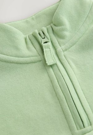 Lichtgroene sweatshirt met een hoge kraag, voorzien van een halve rits en zachte, gestructureerde stof. Naaddetails zijn zichtbaar langs de randen.