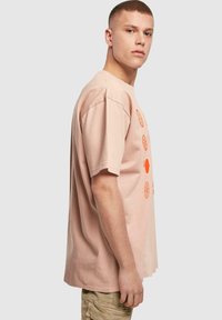 Helles pinkes Baumwoll-T-Shirt mit großen orangefarbenen Grafiken, kurzen Ärmeln, lockerer Passform und Rundhalsausschnitt.