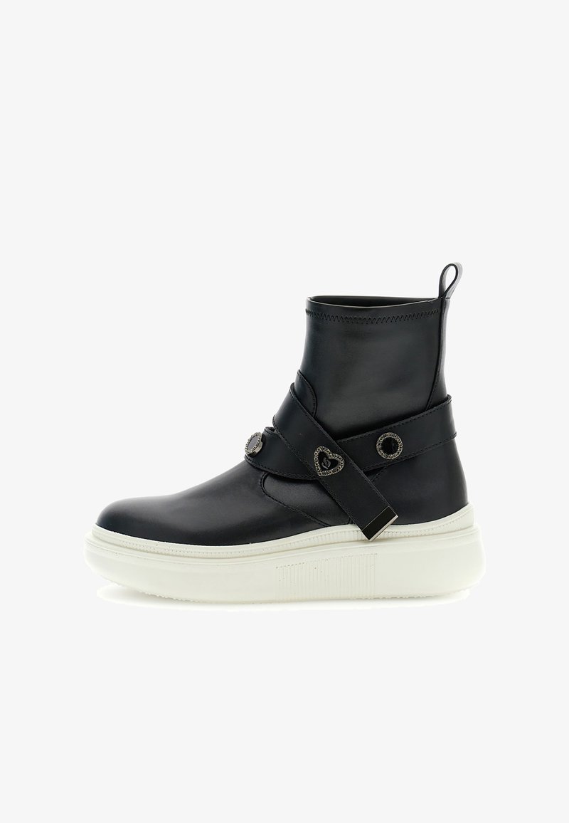 Black leather ankle boot with a rounded toe, white textured sole, and crossover strap featuring heart-shaped metallic accents.