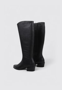 Bottes en cuir noir montantes, à bout rond, avec un petit talon carré et une fermeture éclair à l'arrière. Texture lisse avec un design simple et épuré.