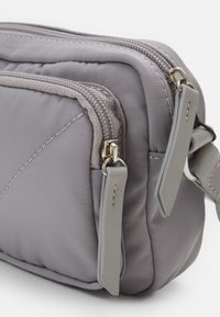 Grå nylon skuldertaske med flere rum, udstyret med sølvfarvede lynlåse, flade grå accenter og diskrete quiltede syningsdetaljer.