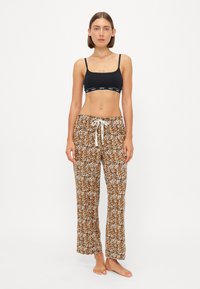 Svart bh med logoband, tillsammans med lätta, beige mönstrade pyjamasbyxor med blommönster och elastisk dragsko i midjan.