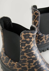 Leopardimustriga pahkluu saapad musta elastse küljeosaga, valmistatud läikivast materjalist ja tekstuurse tallaga pidamise parandamiseks.