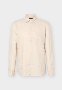 Μπεζ πουκάμισο με μακριά μανίκια, κουμπωτό με μανσέτες, με αιχμηρό γιακά και τσέπη στο στήθος, εμφανίζεται από μπροστά μπροστά σε ένα απλό φόντο.