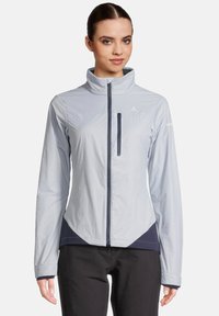 Veste légère bleu clair avec un col haut, fermeture éclair et une poche poitrine ; présente des accents navy et un design ajusté.