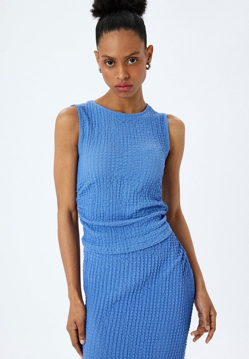 Blauwe gestructureerde mouwloze jurk met een aansluitende silhouette, voorzien van een geplooide accent aan de zijkant en een gladde, ronde halslijn.