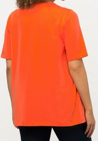 Camiseta de manga corta naranja, hecha de algodón suave, con un corte relajado. Diseño sencillo y cuello redondo clásico.