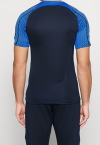 Marinblå atletisk t-shirt med ärmar i blått geometriskt mönster, kortärmad, rund hals och en slät textur, designad för aktivt bruk.