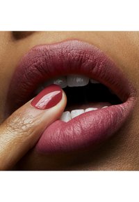 Leppestift i en rik bærfarge på fyldige lepper, akkompagnert av en blank rød manikyr. Leppene ser glatte ut med en matt finish.