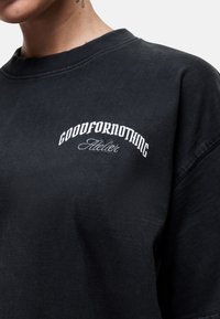 Zwarte sweatshirt van katoen met een ronde hals en een vintage-stijl wit geborduurd logo op de borst. Zachte textuur.
