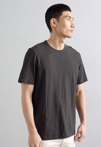 Dark gray cotton t-shirt with short sleeves, crew neckline, and a simple, unadorned design. Smooth texture, relaxed fit.