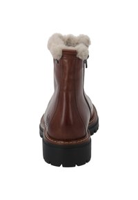 Botín de cuero marrón hasta el tobillo con cuello de piel sintética, suela de goma negra y detalle de cremallera lateral. Diseñado para ofrecer calidez y comodidad.