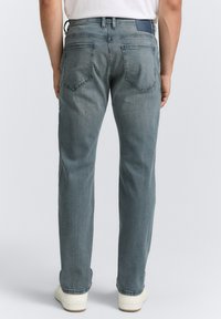 Lichtblauwe denim jeans met een rechte pijp ontwerp, vijf zakken en een leren label op de achterkant van de tailleband. De textuur is glad.