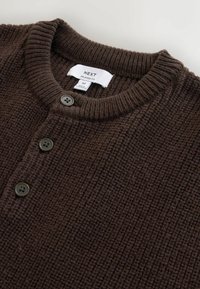 Brown knit cardigan made from textured material, featuring a round neck, three buttons on the front, and a tag indicating relaxed fit.