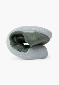 Botte en textile vert à enfiler avec une semelle en caoutchouc blanc, présentant une forme arrondie et une surface légèrement texturée, conçue pour le confort et la facilité d'enfilage.