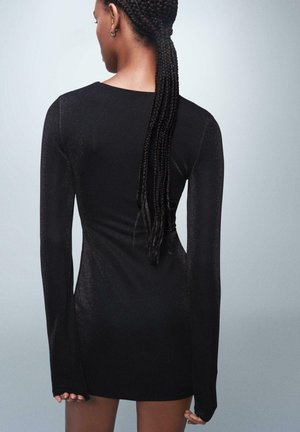 Rochie neagră cu mâneci lungi, cu un design ajustat și textură strălucitoare, având un guler înalt și lungime până la mijlocul coapsei, punând în evidență o siluetă elegantă.