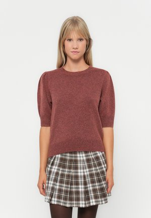 Pull en maille bordeaux avec des manches courtes bouffantes, un col rond et une coupe décontractée, associé à une jupe plissée à carreaux dans des tons marron et blanc.