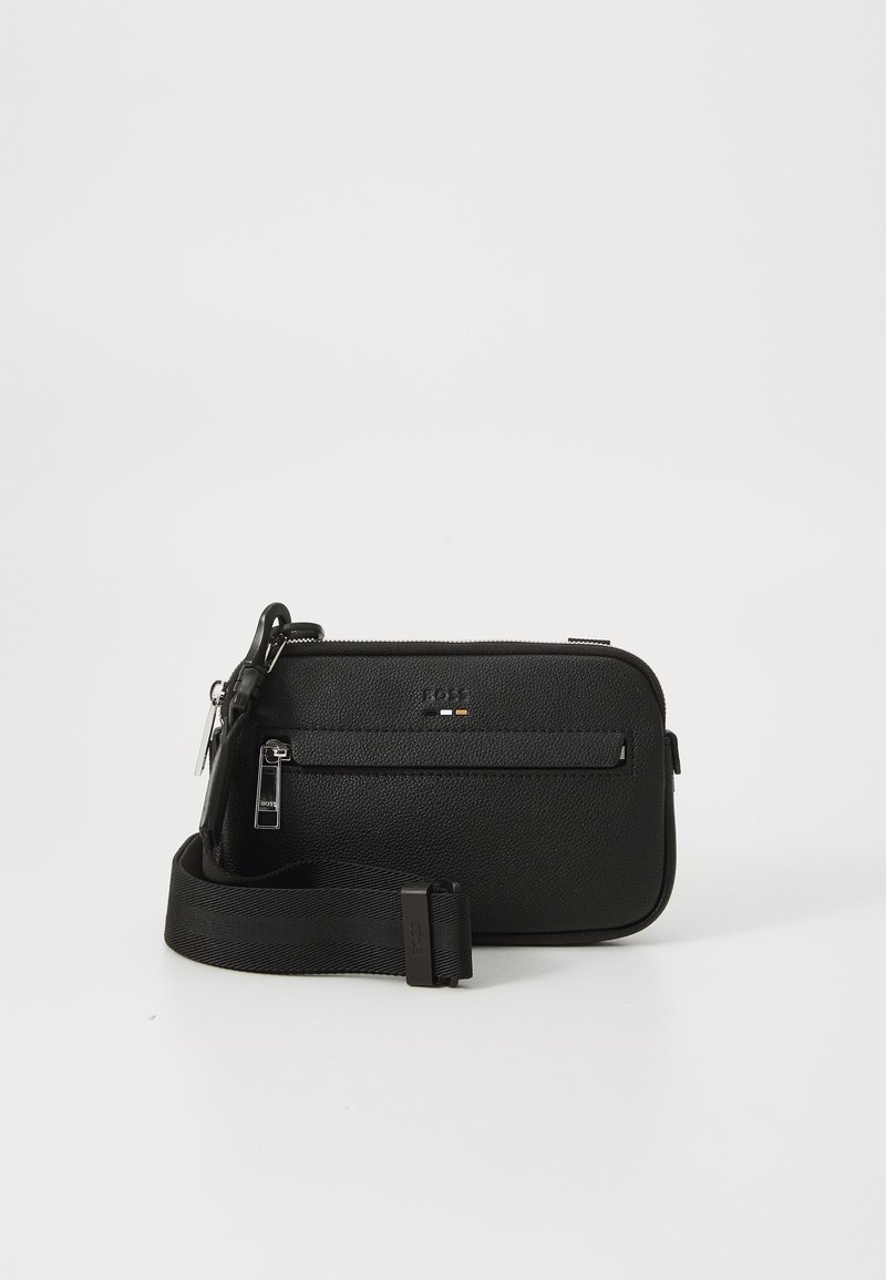 Black leather crossbody bag with textured surface, zippered compartments, adjustable strap, and subtle brand logo on the front.