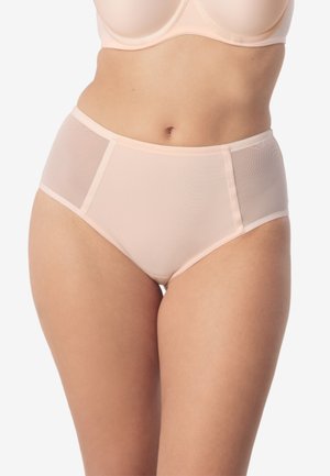 Kobieta w jasno-beżowym biustonoszu i majtkach z wysokim stanem z siateczkowymi panelami bocznymi, stojąca na gładkim, jasnym tle.