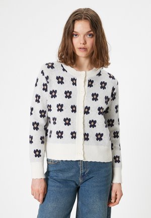 Vitt stickat cardigans med marinblått blommönster, rund halsringning, ribbade ärmslut och nederkant. Har knappstängning fram.