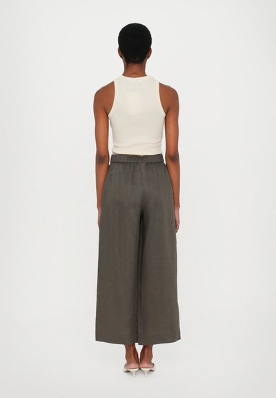 Κρέμα αμάνικο τοπ συνδυασμένο με ψηλόμεσες, φαρδιές ελαιόχρωμες παντελόνες. Λείο ύφασμα, τσάκιση στη μέση και διακριτική πτώση.