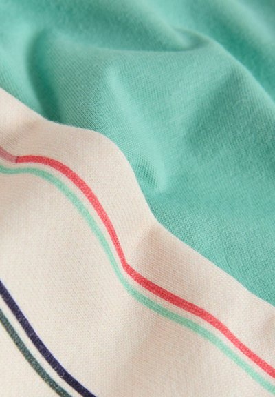 Blødt stof har en mintgrøn sektion og et cremefarvet område med røde, grønne, marineblå og mørk tealfarvede striber, der viser blide folder og tekstur.