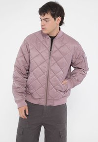 Quilted bomber jacket in a muted pink color, features ribbed cuffs and hem, zip closure, and side pockets. Smooth texture with a modern fit.