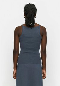 Débardeur ajusté bleu foncé à côtes avec fines bretelles, présentant une texture lisse et un ourlet légèrement évasé à la taille.