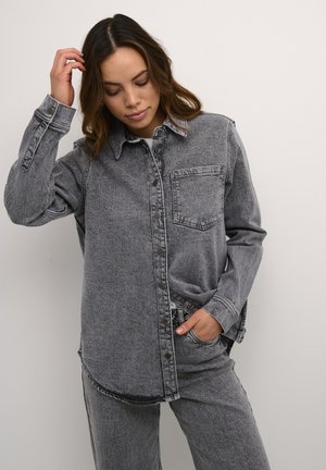 Grå denimskjorte med knaplukning foran, brystlomme og lange ærmer. Har en afslappet pasform og let tekstur.