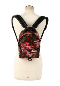 Sac à dos de créateur marron avec des motifs de feuilles et de points rouges et roses, bretelles noires rembourrées, présenté sur un torse de mannequin blanc.