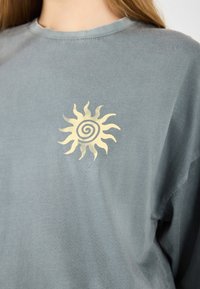 Gray cotton t-shirt featuring a yellow sun graphic with a spiral in the center. Loose fit, round neckline, and soft texture.