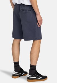 Navy blue sweat shorts made of soft cotton blend, featuring an elastic waistband and a rear pocket with a rounded opening.