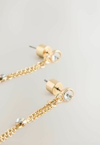 Gold-tone earrings featuring a chain design with a clear crystal accent, smooth finish, and stud backing.