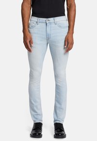 Jasnoniebieskie rurki z lekko przetartym wykończeniem, klasyczny design pięciu kieszeni oraz zamek błyskawiczny. W zestawieniu z czarnymi sznurowanymi butami.