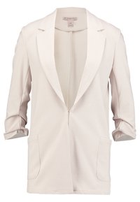 Svetle béžový blazer vyrobený z texturované tkaniny. Obsahuje klopové límce, otevřený přední díl a dvě přední kapsy. Rukávy jsou vyhrnuté do délky lokte.