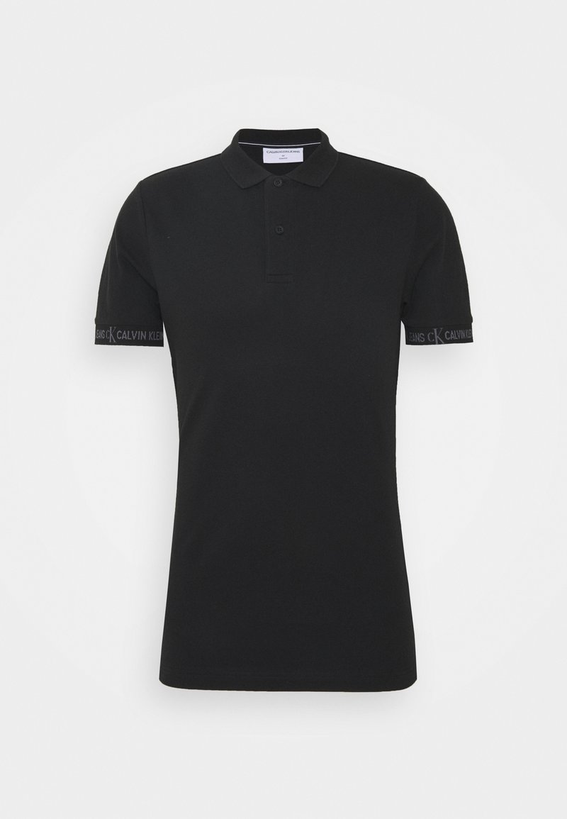 Polo noir avec un col classique, des manches courtes, une patte de boutonnage à deux boutons et le logo Calvin Klein affiché en évidence sur le poignet.