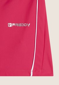 Pantalones cortos deportivos rosas hechos de una tela suave, con acentos blancos y un logo plateado brillante "FREDDY" en el lado izquierdo.