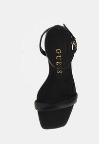 Sandal con tacco alto nero, con tomaia in pelle liscia, cinturino alla caviglia regolabile e design con punta quadrata. Logo dorato sulla soletta.