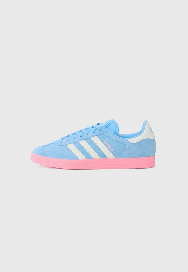 Sneakers en suède bleu avec une semelle en caoutchouc rose, arborant trois rayures blanches et un logo 'Gazelle' sur le côté. Accents bleu clair sur la languette.