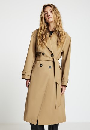 Beiger Trenchcoat mit doppelt geknöpftem Vorderteil, schwarzen Knöpfen, tailliertem Gürtel und weitem Kragen. Hergestellt aus einem glatten Stoff mit geradem Schnitt.