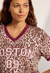 T-shirt med leopardmönster och vinröda detaljer. Har en V-ringning och fet text "BOSTON 89" i vitt. Mjuk tygstruktur.