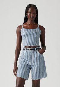 Top cropped de ganga riscas azuis e brancas com alças largas, combinado com calções de cintura alta de correspondência e um cinto preto, apresentando bolsos frontais.