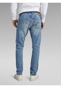 Ljusblå denimjeans med lös passform, synliga sömmar, två bakfickor och en märkesetikett ovanför midjebandet.