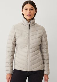 Lys grå isoleret jakke med lynlås foran, h�øj krave og chevronmønster. Glat tekstur, tætsiddende design, perfekt til koldt vejr.