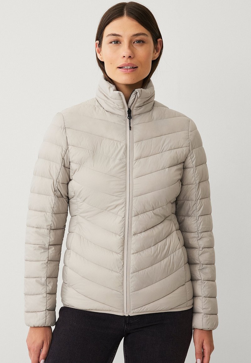 Hellgraue isolierte Jacke mit Reißverschluss vorne, hohem Kragen und Zickzackmuster. Glatte Textur, taillierte Passform, perfekt für kaltes Wetter.