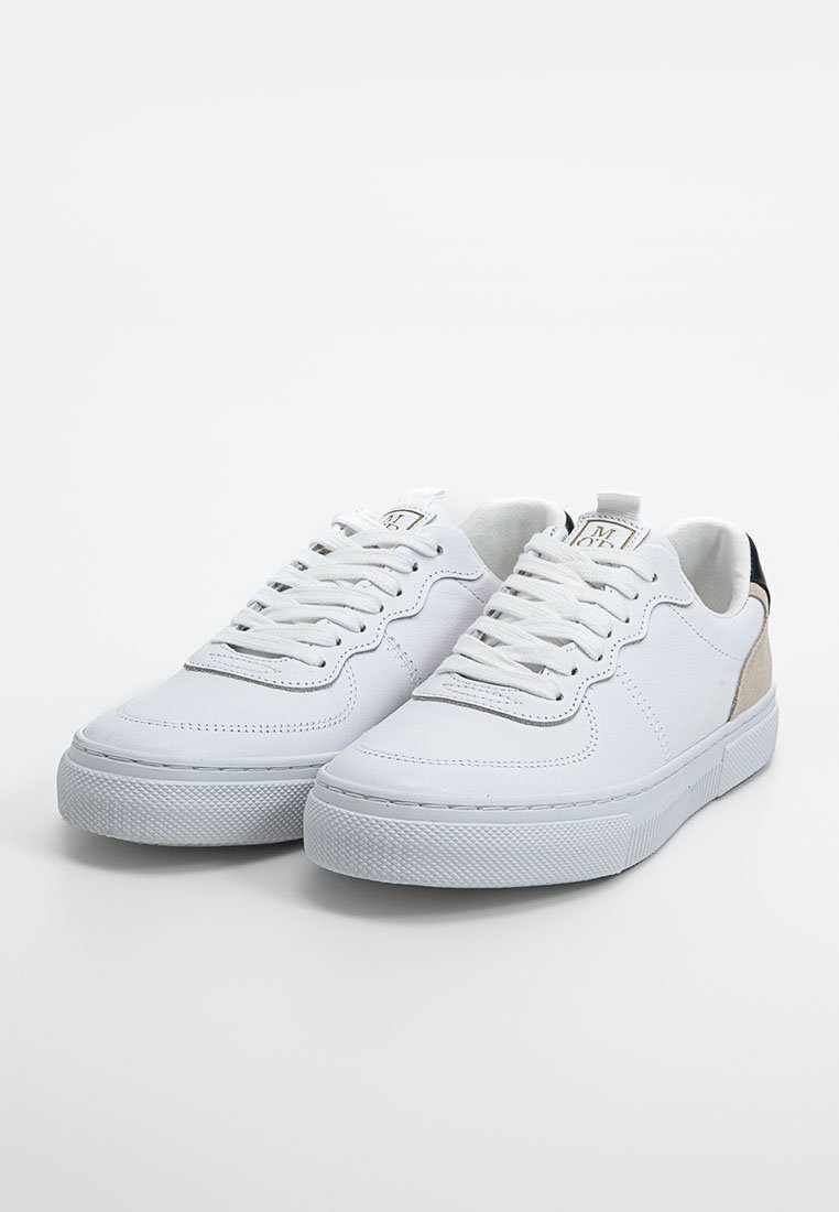 Weiße Niedrigschnitt-Sneaker mit Schnürsenkeln, strukturierten Gummisohlen, beigem Fersenakzent und markiertem Zunge auf einem schlichten Hintergrund.