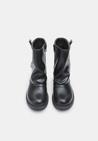 Schwarze Leder-Stiefeletten mit einem lässigen Design, runden Zehen, seitlichen Reißverschlüssen und strukturierten Akzenten entlang des oberen Randes.
