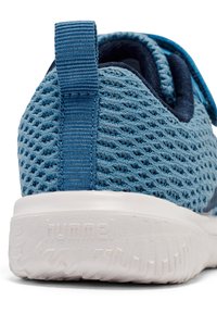 Zapatilla deportiva de malla azul con un diseño texturizado, un refuerzo en la parte del talón y una suela de goma blanca con un patrón antideslizante.