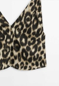 Haut sans manches à col en V avec motif léopard beige et noir sur tissu léger.